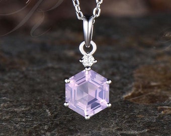 May include: A silver chain necklace with a hexagonal pink gemstone pendant. The pendant has a small diamond accent above the gemstone.