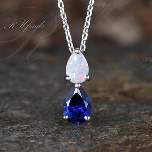 May include: A silver chain necklace with a teardrop-shaped opal pendant and a teardrop-shaped blue sapphire pendant.