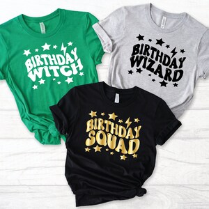 Peut inclure: Trois t-shirts avec des designs différents. Le premier t-shirt est vert avec du texte blanc qui dit "Birthday Witch". Le deuxième t-shirt est gris avec du texte noir qui dit "Birthday Wizard". Le troisième t-shirt est noir avec du texte doré qui dit "Birthday Squad".