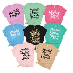May include: Set of ten t-shirts with various Harry Potter themed designs. The shirts are in different colors, including pink, green, blue, black, and beige. The designs feature text and graphics related to the Harry Potter universe, such as "Mischief Maker", "Mischief Runs in the Family", and "I Solemnly Swear It's My 9th Birthday".
