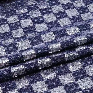 May include: A navy blue fabric with a checkered pattern made of silver sequins.