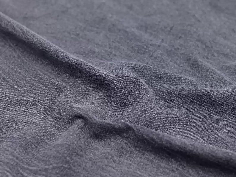 Puede incluir: Primer plano de una tela gris oscura con una superficie texturizada. La tela est&aacute; arrugada y tiene una sensaci&oacute;n suave y c&oacute;moda.