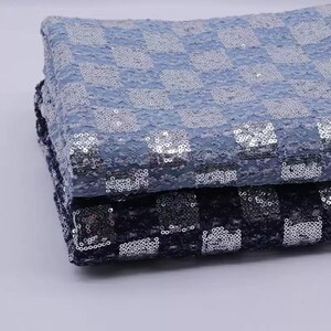 May include: Two pieces of fabric with a checkered pattern. The top piece is light blue with silver sequins, and the bottom piece is dark blue with silver sequins.