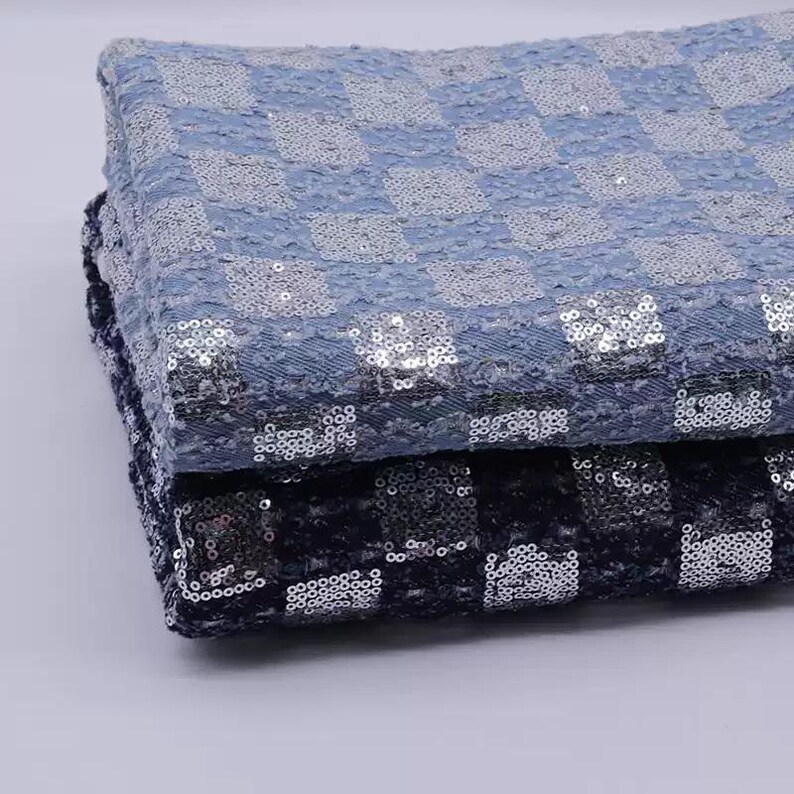 May include: Two pieces of fabric with a checkered pattern. The top piece is light blue with silver sequins, and the bottom piece is dark blue with silver sequins.