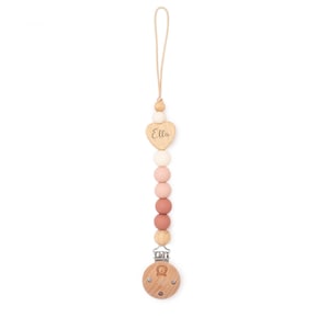 Op de afbeelding: Een houten en siliconen baby-bijtje met een hartvormige hanger waarop "Ella" staat. De bijtje heeft een clip om aan kleding te bevestigen.