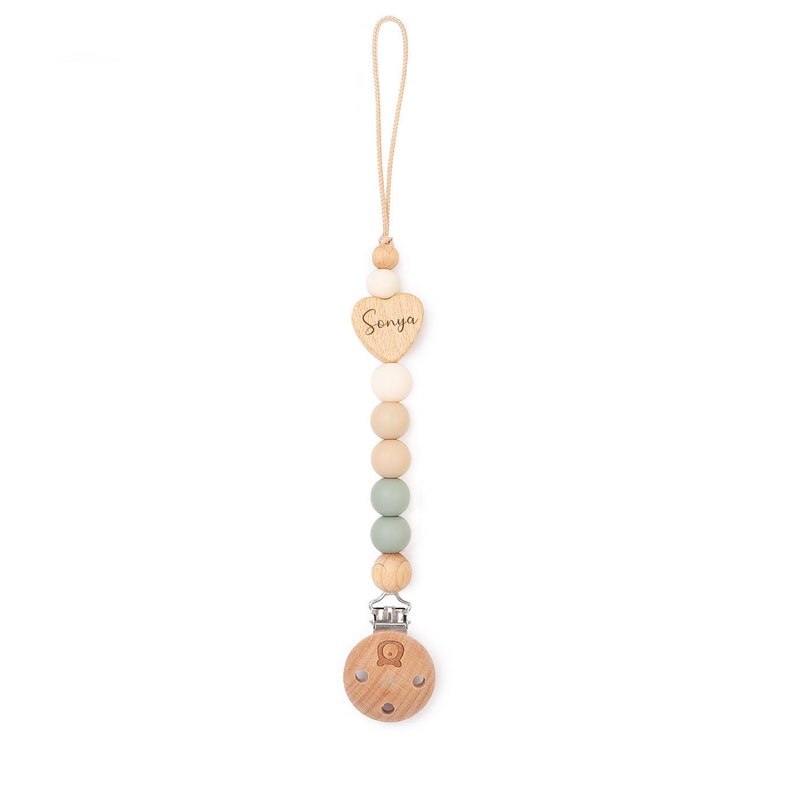 Op de afbeelding: Een houten baby-bijtje met een hartvormige hanger waarop "Sonya" staat. De bijtje is gemaakt van natuurlijke houten kralen en heeft een clip om aan kleding te bevestigen.