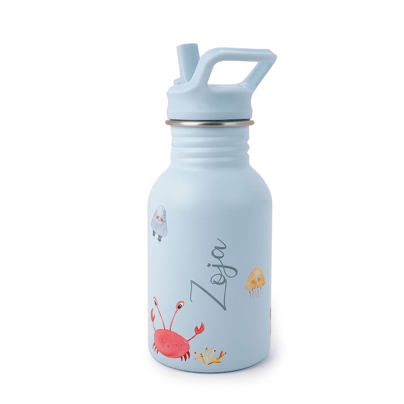 May include: A light blue stainless steel water bottle with a straw lid and a handle. The bottle has a colorful design of sea creatures, including a crab, a jellyfish, and a penguin. The name "Zoja" is written on the bottle.