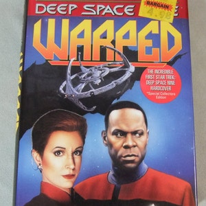 May include: A hardcover book titled "Star Trek: Deep Space Nine Warped" by K.W. Jeter. The cover features a space station, a woman with red hair, and a man with short black hair. The book is a special collectors edition.