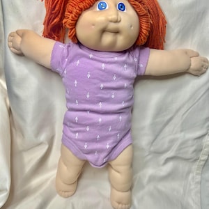 May include: A white ceramic mug with a black handle and the text "But First, Coffee" in a bold, black font. The mug is set against a blurred background, suggesting a cozy setting.