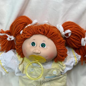 May include: A white ceramic mug with a black handle and the text "But First, Coffee" in a black, bold font. The mug is on a white surface.