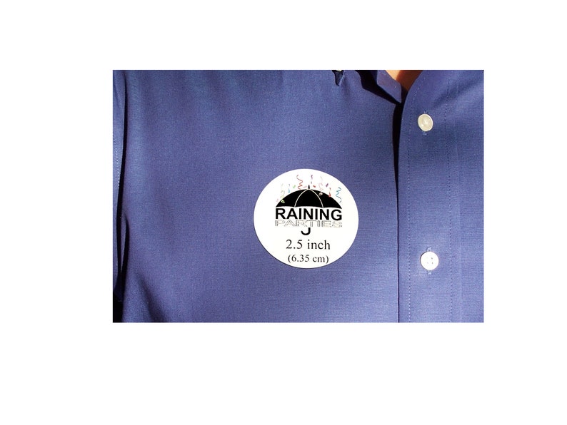 Puede incluir: Una pegatina redonda blanca con un paraguas negro y el texto "RAINING FOR SUCCESS" en negro. La pegatina tambi&eacute;n tiene confeti de colores alrededor del paraguas y el texto "2,5 pulgadas (6,35 cm)".
