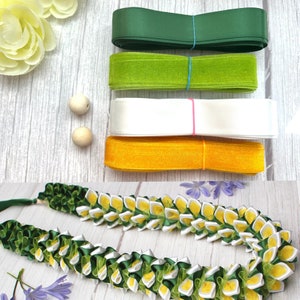 May include: An assortment of colorful ribbons in green, lime green, white, and gold, along with a handmade lei. The lei is made of green, white, and yellow fabric. Two wooden beads and a few yellow flowers are also visible.