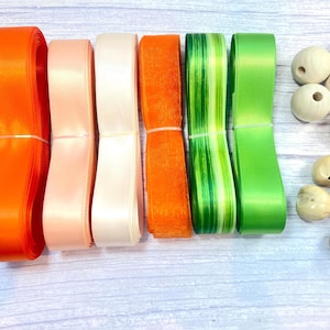 Peut inclure: Un assortiment de rubans color&eacute;s et de perles en bois. Les rubans sont dans les tons orange, rose, blanc, vert et un motif ray&eacute; vert et blanc. Les perles en bois sont marron clair et ont des trous.