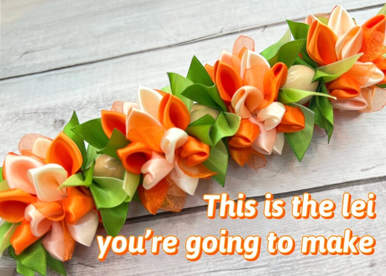 Peut inclure: Un lei fait &agrave; la main avec des fleurs en ruban orange, blanc et p&ecirc;che avec des feuilles vertes. Le texte "This is the lei you're going to make" est affich&eacute; en lettres orange.