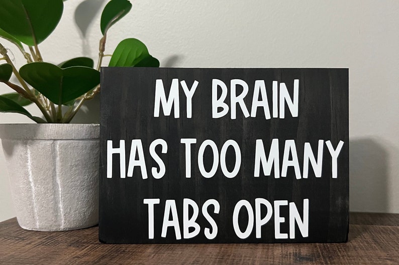 K&ouml;nnte beinhalten: Schwarzes Holzschild mit wei&szlig;em Text, der "Mein Gehirn hat zu viele Tabs offen" lautet.