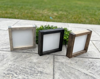 May include: Three wooden shadow boxes with white mats. The boxes are in different shades of wood: gray, black, and brown.