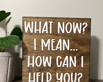 May include: Wooden sign with the text "What now? I mean... How can I help you?" in white lettering.