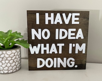 Puede incluir: Un letrero de madera marrón con letras blancas que dice "No tengo ni idea de lo que estoy haciendo."