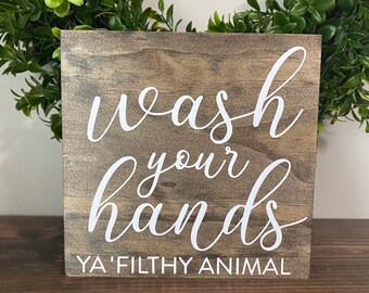 May include: A wooden sign with the text "wash your hands ya' filthy animal" in white lettering.