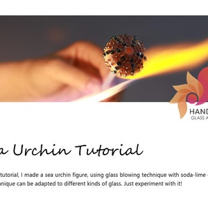 May include: A close-up of a glass sea urchin being heated with a torch. The glass is a light brown colour and has a textured surface. The torch is creating a bright orange flame. The image is titled "Sea Urchin Tutorial" and includes the text "HANDE ERBÜK GLASS ARTIST".
