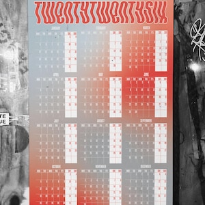 Könnte beinhalten: Ein 2026-Kalender mit einem Farbverlauf von Rot nach Blau. Das Wort "TWENTYTWENTYSIX" steht oben in roter, stilisierter Schrift. Jeder Monat wird mit Daten in einem Rasterformat angezeigt.