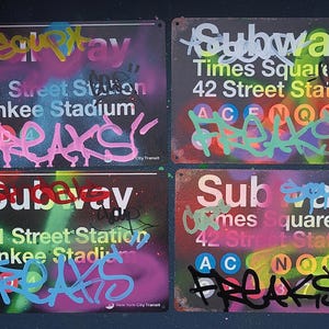 May include: Four metal signs with graffiti art. Each sign features the word "Subway" and station names like "Times Square" and "Yankee Stadium." The signs are painted with vibrant colours and graffiti tags.