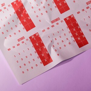 May include: A calendar with red highlighted dates on a white background. Months visible include July, October, November, and December. The calendar is on a purple surface.