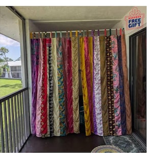 May include: A vibrant set of patchwork curtains, made from a variety of fabrics in shades of pink, purple, yellow, and brown. The curtains hang from a rod. The text "ASSURED FREE GIFT" is visible in the upper right corner.