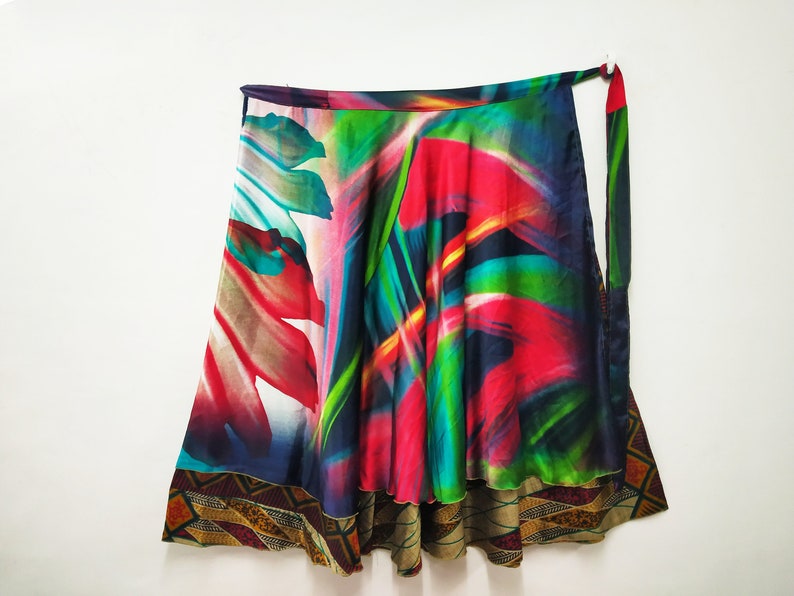 May include: A colorful wrap skirt with a vibrant abstract print featuring shades of red, green, blue, and pink. The skirt has a brown and gold trim around the bottom.