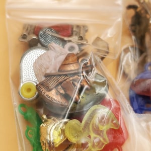May include: A clear plastic bag containing a collection of small charms and trinkets. The charms include a miniature sombrero, a horse, and a green leaf-shaped charm. Some charms have the text "HELLO HANDSOME".
