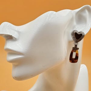 May include: A white ceramic mug with a black handle and the text "But First, Coffee" in a black, handwritten-style font. The mug is on a white surface.