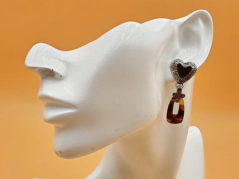 May include: A white ceramic mug with a black handle and the text "But First, Coffee" in a black, handwritten-style font. The mug is on a white surface.