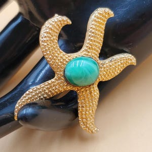 vintage small gold tone starfish pin with green center stone