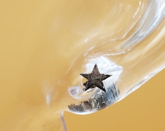 May include: A silver star-shaped earring stud on a clear plastic display stand.