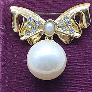 Vintage gold tone rhinestone bow brooch with large dangling faux pearl