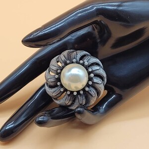 Vintage dark metal flower brooch with large faux pearl center and clear rhinestone accents