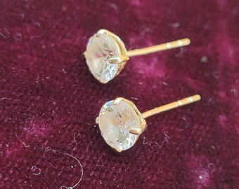 May include: A pair of gold stud earrings with clear round stones.