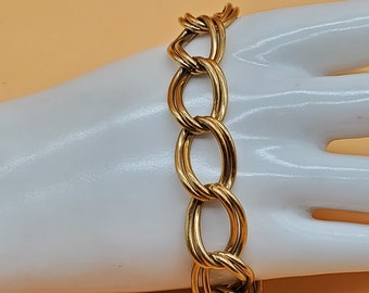 May include: A gold chain bracelet with large, oval-shaped links. The links are twisted and interlocked, creating a unique and stylish design.