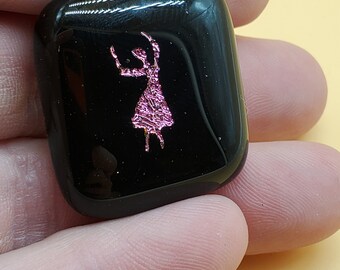 Puede incluir: Un pisapapeles de vidrio negro con una silueta rosa de una persona con los brazos levantados.