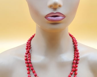 May include: A double-strand red beaded necklace. The necklace features faceted beads in a vibrant red hue, strung together to create a layered effect. The beads are evenly spaced, and the necklace is displayed on a mannequin.