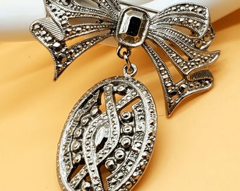 Vintage 1928 silver tone bow brooch with dangling medallion