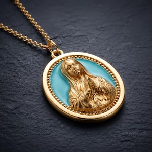 Peut inclure: Un collier pendentif ovale doré présentant un relief d'une silhouette aux mains jointes en prière. La figure centrale est placée sur un fond en émail turquoise vif, encadrée par une bordure dorée perlée, fixée à une fine chaîne.