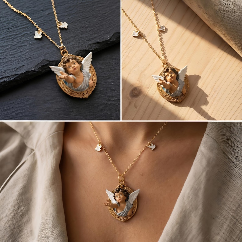 Puede incluir: Collar dorado con un colgante con dise&ntilde;o de querub&iacute;n. El querub&iacute;n tiene alas blancas y est&aacute; enmarcado en un &oacute;valo. El collar tambi&eacute;n tiene peque&ntilde;os adornos blancos. El collar se muestra sobre una superficie negra, una superficie de madera y siendo usado.
