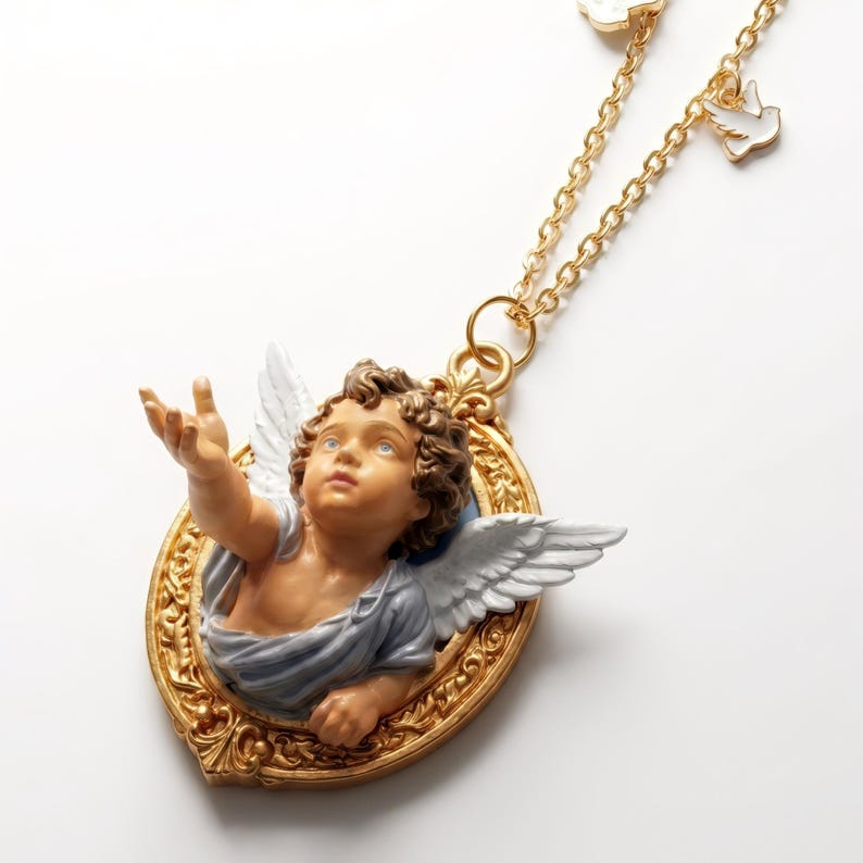 Puede incluir: Un collar dorado con un colgante con dise&ntilde;o de querub&iacute;n. El querub&iacute;n est&aacute; en un marco ovalado dorado, con alas blancas y una prenda azul y blanca. El collar tambi&eacute;n tiene peque&ntilde;os dijes de paloma blanca.