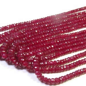 May include: Strands of faceted, deep red ruby beads. The beads are small and uniform in size, strung together to create multiple necklaces. The ruby beads have a polished, reflective surface, and are displayed against a white background.
