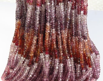 May include: A collection of faceted gemstone beads in shades of red, pink, and purple. The beads are strung together, creating a cascading effect. The gemstones have a sparkling, polished appearance.