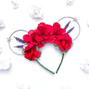May include: Red flower headband with silver wire and purple flowers. The headband is on a white background with white flowers scattered around it.