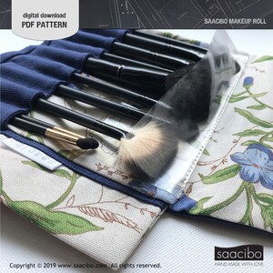 Pu&ograve; includere: Un astuccio per il trucco con stampa floreale e interno blu navy, contenente diversi pennelli per il trucco con manico nero. L'astuccio &egrave; aperto, rivelando i pennelli e una copertura di plastica trasparente. Il testo sull'astuccio recita "SAACIBO MAKEUP ROLL" e "digital download PDF PATTERN".
