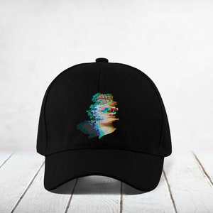 May include: Black baseball cap featuring a colourful, glitched image of a person's face on the front.