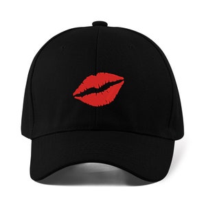 以下が含まれることがあります： 前面に赤い唇のプリントが施された黒い野球帽